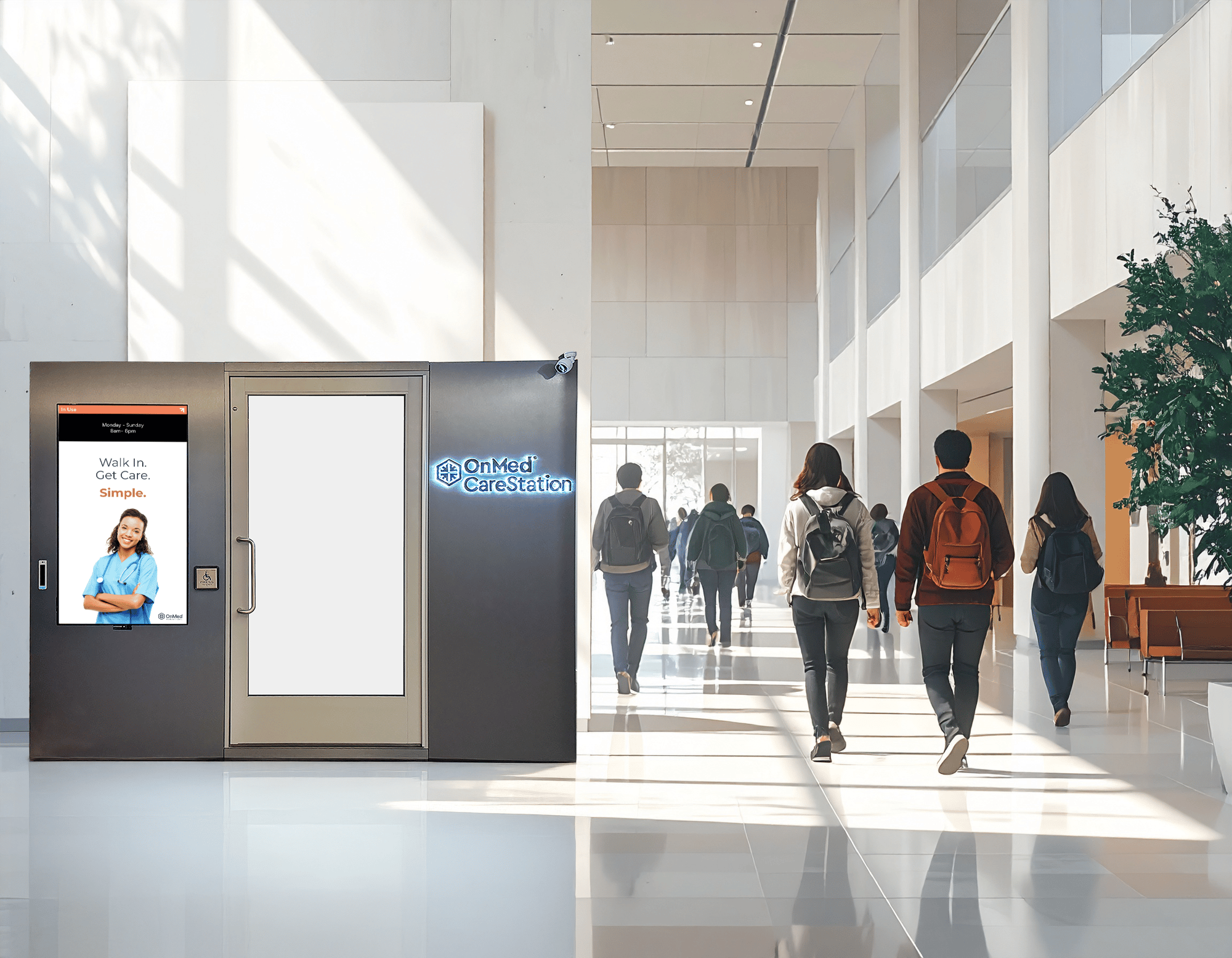 OnMed CareStation telehealth kiosk in a bright modern university building corridor, with students walking past on their way to class